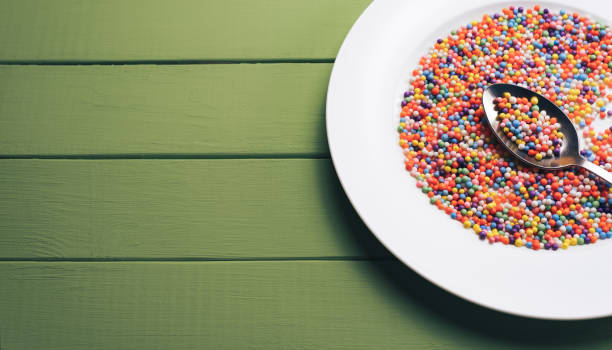 istock White plate with color preparations (vitamins, dyes, flavor enhancers, nutritional supplements, innovative technologies, candy sweets) on an green wooden table background. 1144581276