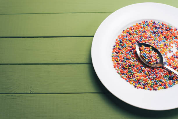 istock White plate with color preparations (vitamins, dyes, flavor enhancers, nutritional supplements, innovative technologies, candy sweets) on an green wooden table background. 1144582291