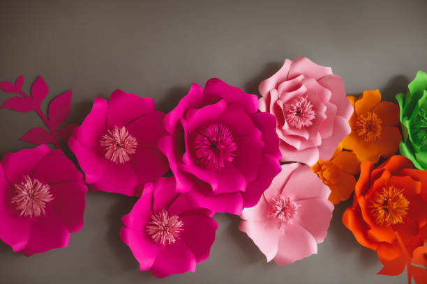 istock Colorful paper flowers on gray wall 1144582493