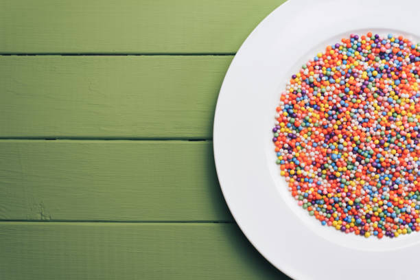 istock White plate with color preparations (vitamins, dyes, flavor enhancers, nutritional supplements, innovative technologies, candy sweets) on an green wooden table background. 1144582792