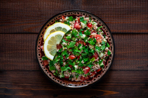 tabbouleh salat auf einem teller, dunkler holzhintergrund. - tabbouleh vegeterian food middle stock-fotos und bilder