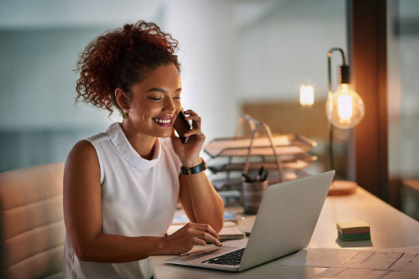 Always be ready when business comes calling Shot of a cheerful young businesswoman taking a phone call while working late in her office answering photos stock pictures, royalty-free photos & images