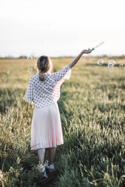 istock Female Hippie Blowing Bubbles All Over The Grass 1144588116