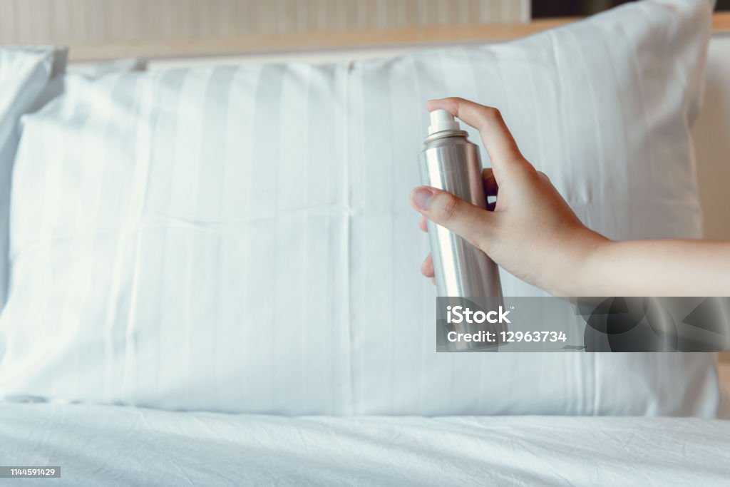 Woman Hand is Spraying Air Freshener into Pillow on Bedroom, Unpleasant Smell and Aromatherapy Concept Woman Hand is Spraying Air Freshener into Pillow on Bedroom, Unpleasant Smell and Aromatherapy Concept. Pillow Stock Photo