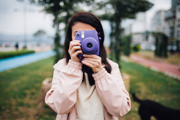 istock Young woman holding instant camer 1144596986