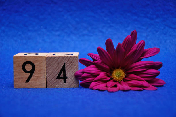 istock Number ninety four with a purple daisy on a blue background 1144597677