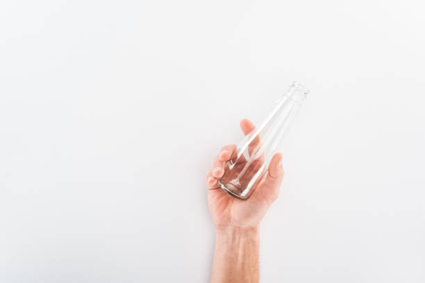 istock Cropped view of man holding empty glass bottle on grey background 1144603791