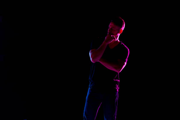istock Handsome man with black shirt with colored gel lighting 1144604332
