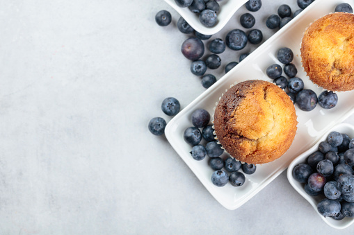 Muffins and blueberry on white kitchen table.  Top view, copy space.