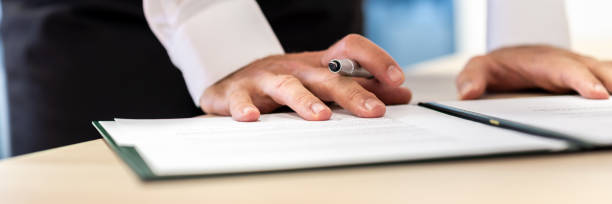 istock Wide view image of businessman holding ink pen leaning on a document 1144610184