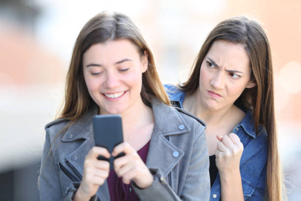 istock Angry woman spying her friend using phone 1144612007
