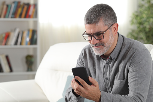Hombre adulto usando un teléfono inteligente en casa photo