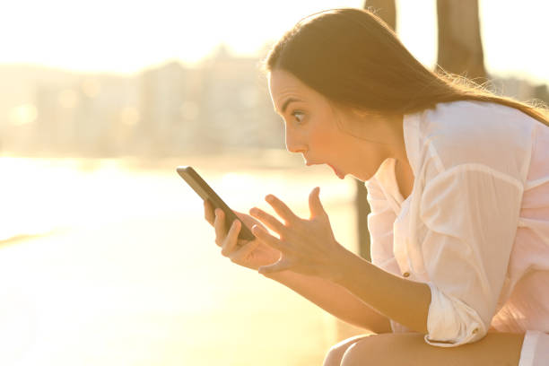 istock Amazed girl finding smart phone content on the beach at sunset 1144612116