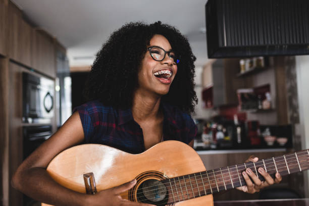 joven adolescente tocando la guitarra - plucking an instrument fotografías e imágenes de stock