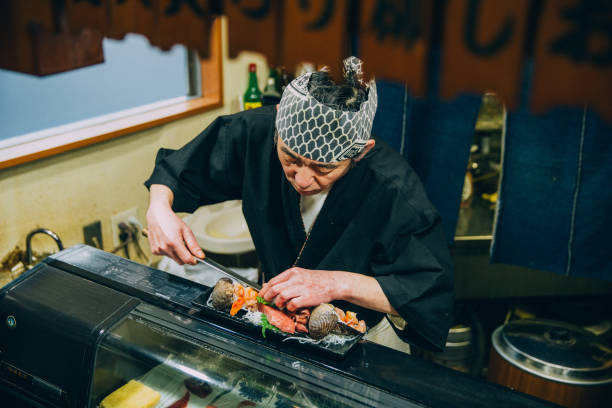 Japanese Chef Preparing Sushi A real Japanese Sushi chef prepares sushi for his restaurant in Tokyo, Japan. He prepares sushi, known as nigiri, for dinner. This traditional Japanese food is being prepared on a wooden platter. japanese chef stock pictures, royalty-free photos & images