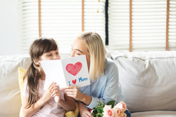 istock Daughter greeting her Mom with roses and postcard. 1144614830