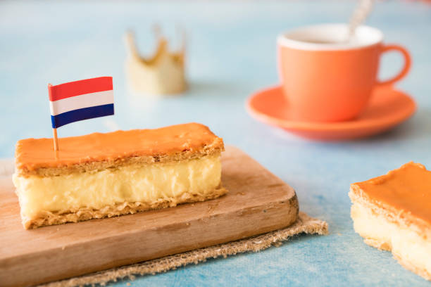 Orange tompouce, traditional Dutch treat with pudding and frosting on national holiday Kings Day (April 27th), in The Netherlands. Dutch breakfast setting for National event Kings Day on the 27th of April, in The Netherlands. Orange tompouce, Cup of coffee, Dutch flag and crown crown headwear photos stock pictures, royalty-free photos & images