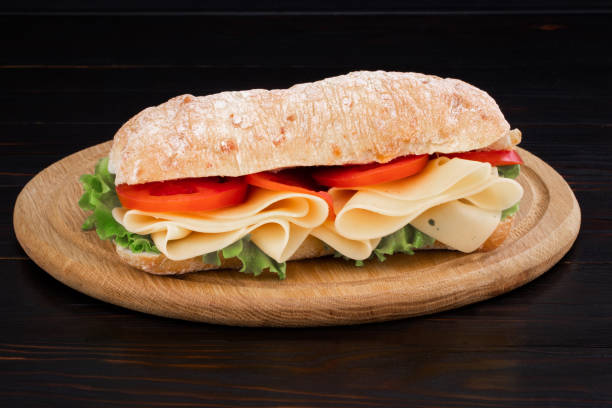 istock Ciabatta sandwich with lettuce , prosciutto and  cheese on wooden board 1144623036