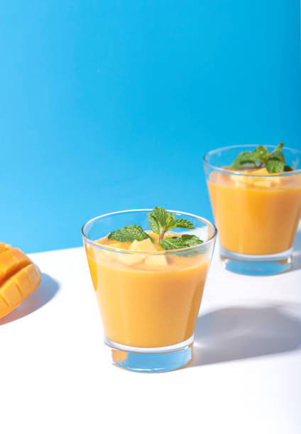 batido de mango fresco y rebanada de mango maduro sobre fondo de color. bebida veraniega. - 2360 fotografías e imágenes de stock