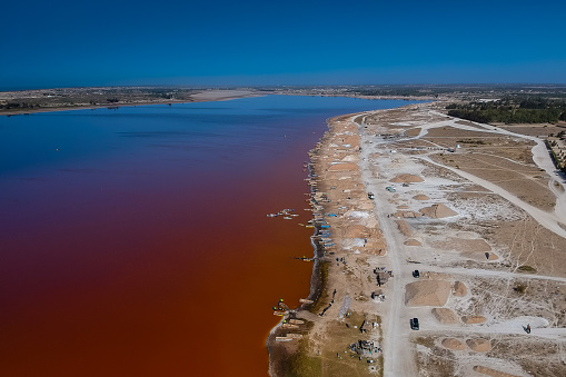 Aerial view of Lac Rose or Lake Retba in Senegal. Pink lake, very rich in salt, showing natural beauty and rich color on a sunny day. View of lake coastline towards the salt harvesting ground in the background.