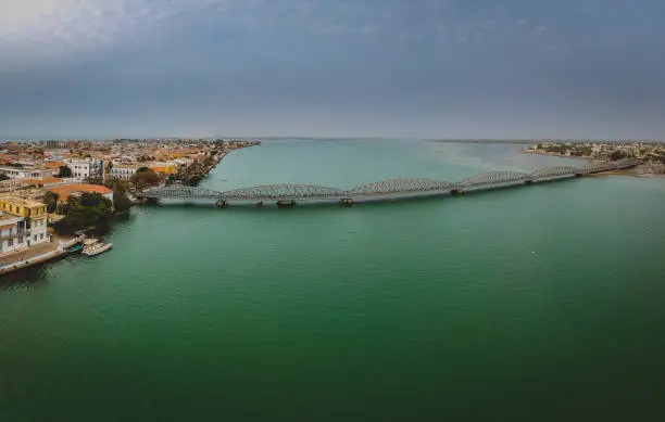 Aerial panorama photo of Senegal river in Sant Louis, Senegal, with the Faidherbe bridge seen connecting the new part of the city on an overcast day.