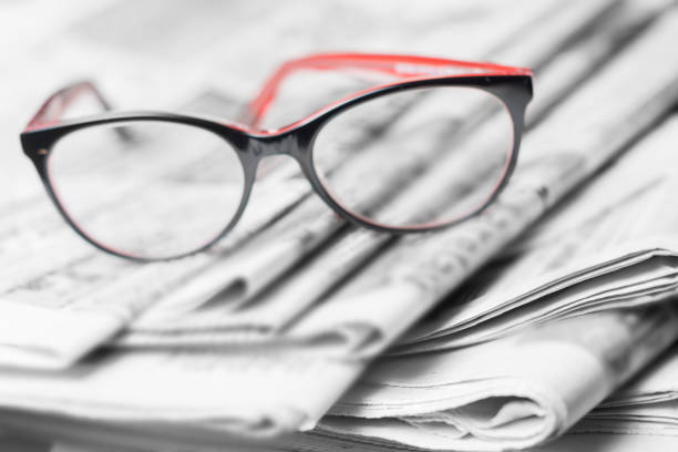 istock News concept, folded newspaper closeup, eyeglasses. 1144628027