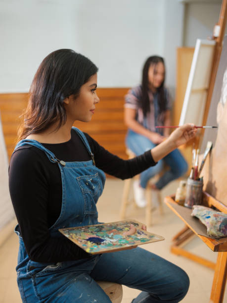 istock Young woman focused painting on an easel 1144631623