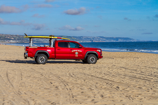 Newport Beach, CA / USA – April 6, 2019: Newport Beach Fire Department Lifeguard truck on beach near the Balboa Peninsula facing the shoreline of Pacific Ocean.