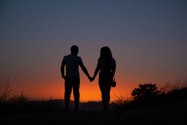 istock Young couple enjoying sunset in the mountains 1144636163