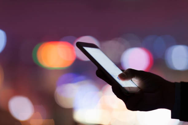 istock Hand holding smart phone in urban area at night 1144636541