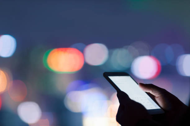 istock Hands holding smart phone in urban area at night 1144636560