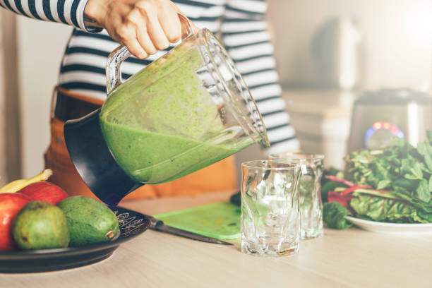 istock woman's hand pouring green smoothie into a glass 1144638219