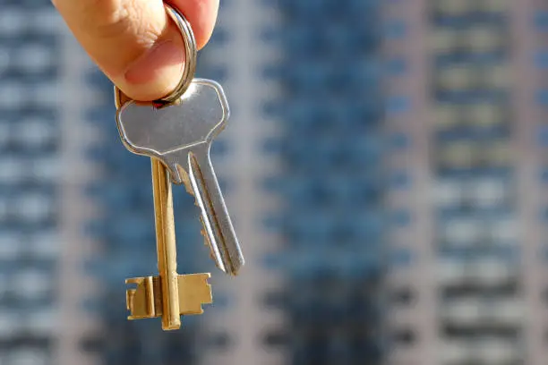 Photo of Real estate agent holding house keys on background of new residential building