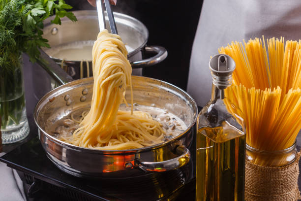 young woman in a gray apron preparing pasta young woman in a gray apron preparing pasta. macaroni stock pictures, royalty-free photos & images