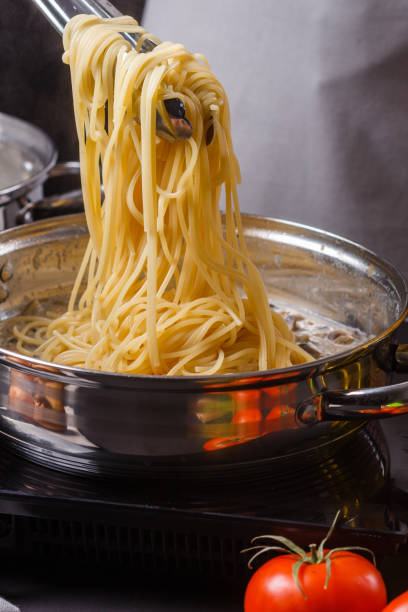 young woman in a gray apron preparing pasta young woman in a gray apron preparing pasta. macaroni stock pictures, royalty-free photos & images