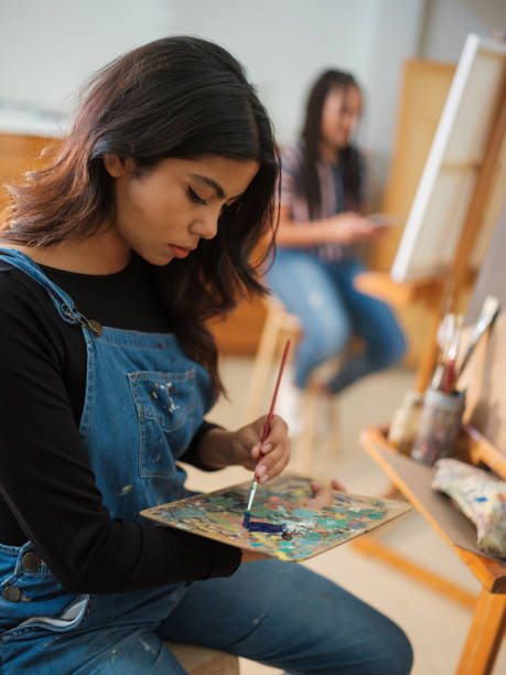 istock Serious female artist using a palette to mix paints. 1144643773