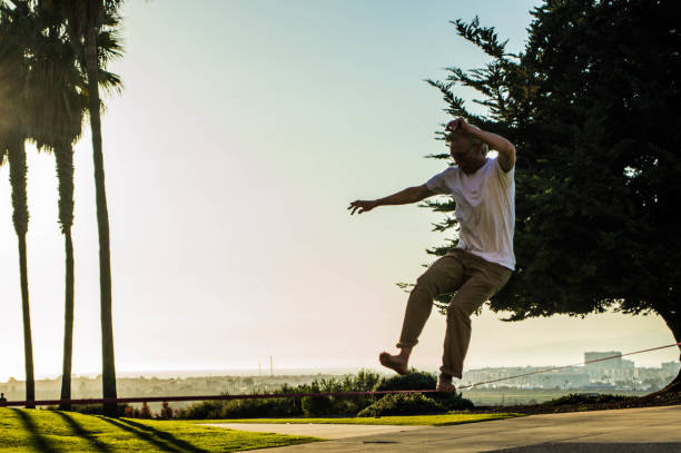 istock Young men walk across a slack line between trees on a sunny day 1144643898