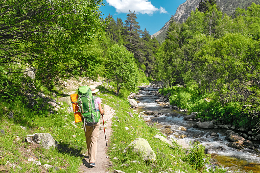 A hiker woman travels along small river during GR11 Hike in Pyrenees mountains
