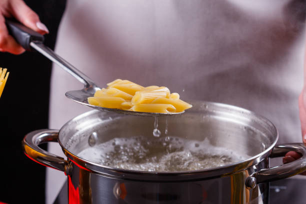 young woman in a gray apron is preparing pasta pesto