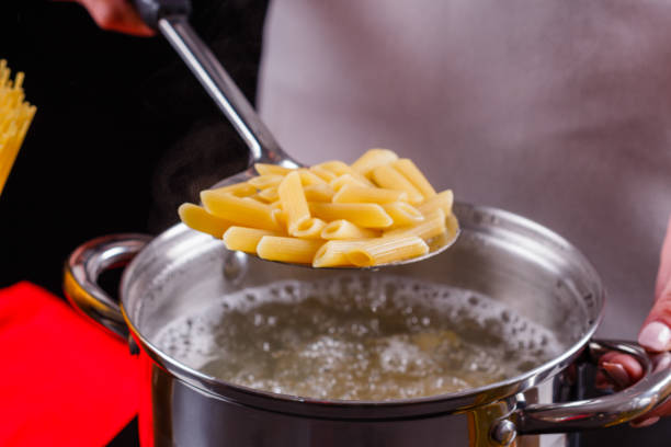 young woman in a gray apron is preparing pasta pesto
