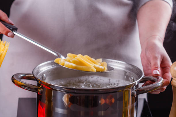 young woman in a gray apron is preparing pasta pesto