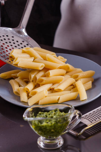 jeune femme dans un tablier gris prépare le pesto de pâtes - macaroni cheese food staple casserole photos et images de collection