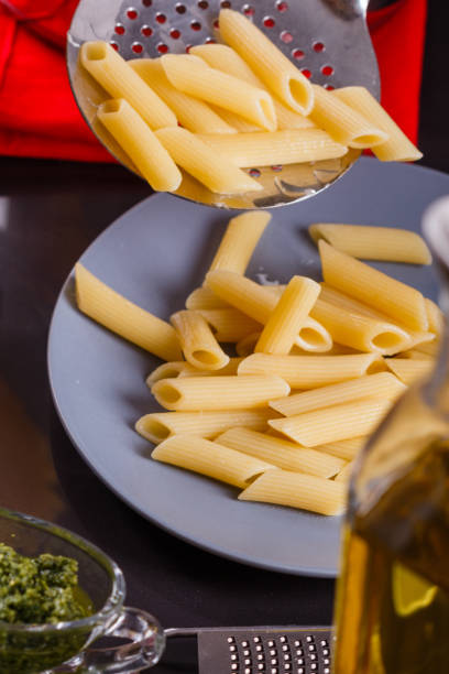 jeune femme dans un tablier gris prépare le pesto de pâtes - macaroni cheese food staple casserole photos et images de collection