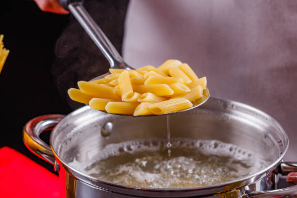 young woman in a gray apron is preparing pasta pesto