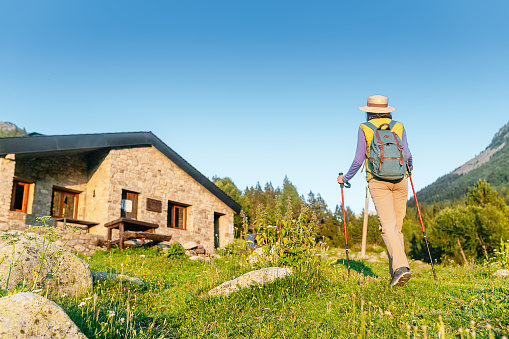 Young woman hiker camping near the beautiful shelter stone hut building in Pyrenees mountains. Hiking and adventure concept