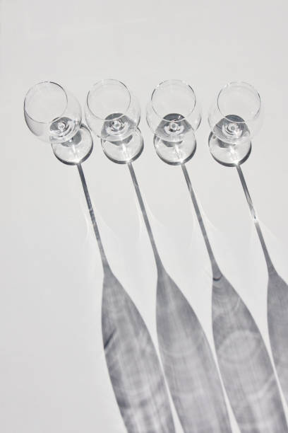 istock Row of four wine glasses. Abstract shadows, sunlight, white background. 1144645910