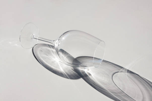 istock Wine glass lying on the table. Abstract shadows, sunlight. 1144645925
