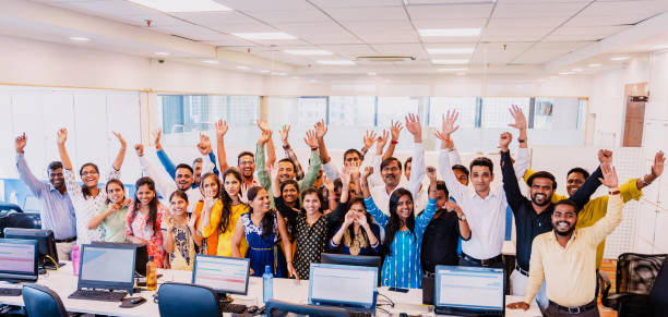 Corporate Group Portrait of Cheering Staff Members Corporate Business, Indian, Office - Large Group of Cheerful Business Executives Looking at the Camera for a Group Portrait at their office large group of people facing camera stock pictures, royalty-free photos & images
