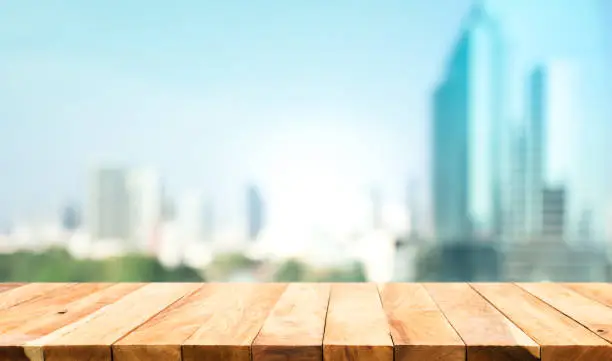 Wood table top on blur window glass,wall background with city view.For montage product display or design key visual layout