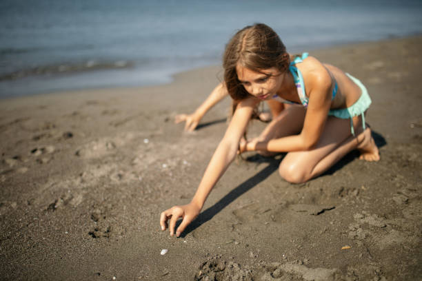 istock Boy and girl picking up shells on the sand beach 1144654654